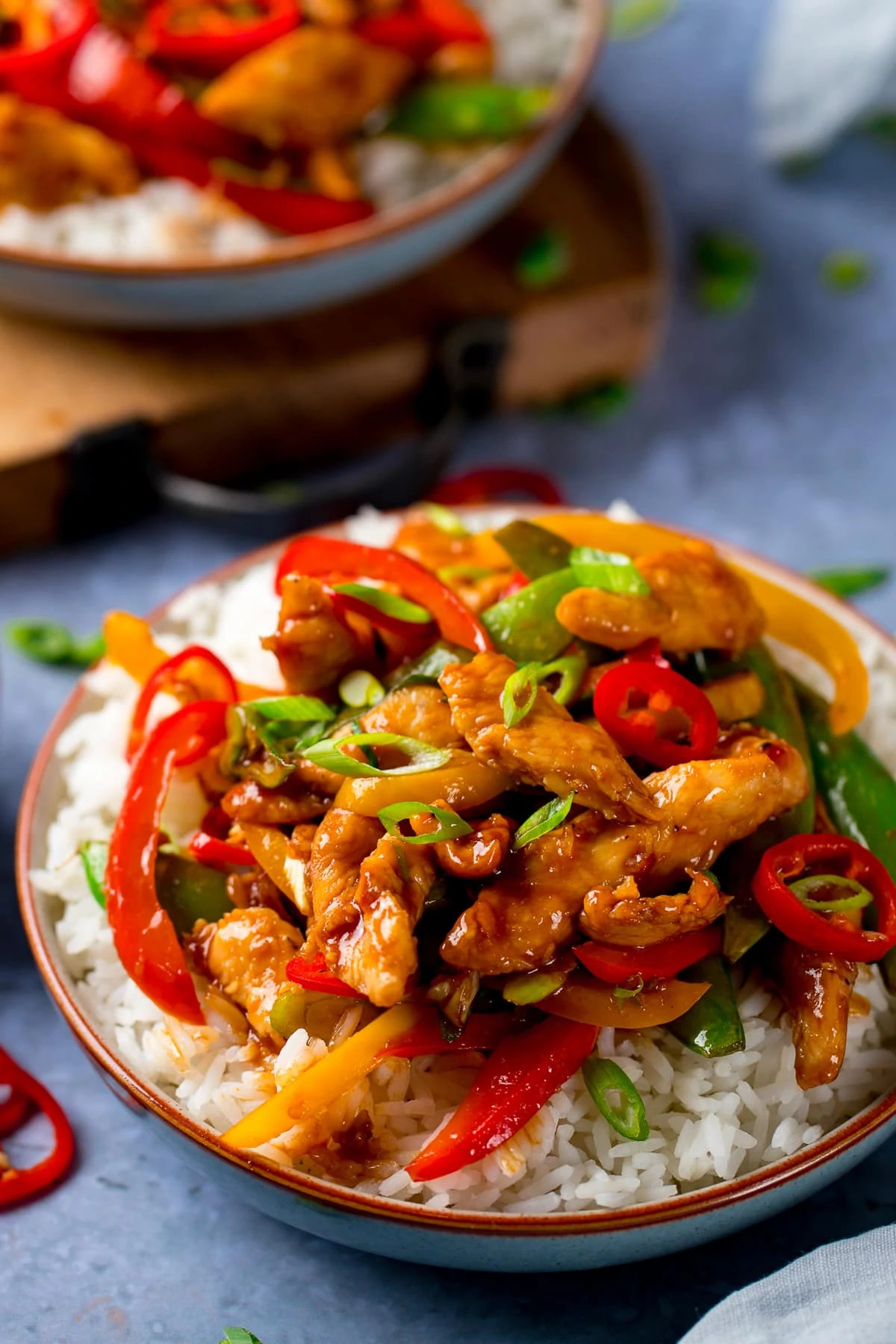 chicken stir fry with rice in a bowl topped with chillies and spring onions
