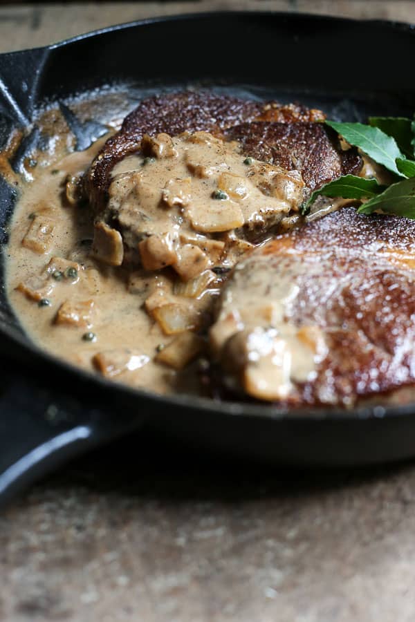 Two steaks in a pan with dairy-free peppercorn sauce