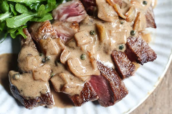 steak on a plate drizzled with dairy-free peppercorn sauce